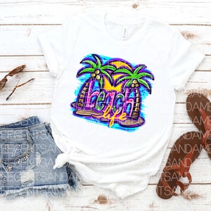 Pu&ograve; includere: Maglietta bianca con un design grafico colorato di palme e il testo "beach life".