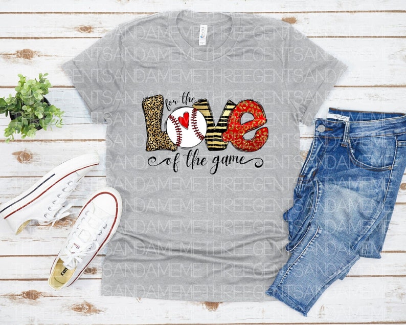 May include: Gray t-shirt with a baseball-themed graphic that says "For the Love of the Game". The graphic features a baseball with a red heart, surrounded by the letters "LOVE" in a leopard print and zebra print.