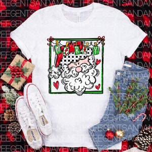 May include: White t-shirt with a graphic of Santa Claus's face in a red and green frame. The frame has the word "Merry" written on it. The graphic is on a white background.