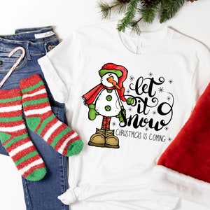 May include: White t-shirt with a snowman graphic and the text "Let it snow. Christmas is coming."