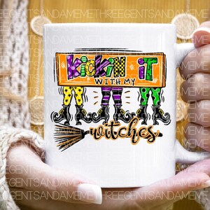 May include: White ceramic mug with a colorful graphic of three witches with broomsticks and the text "Kickin' it with my witches".