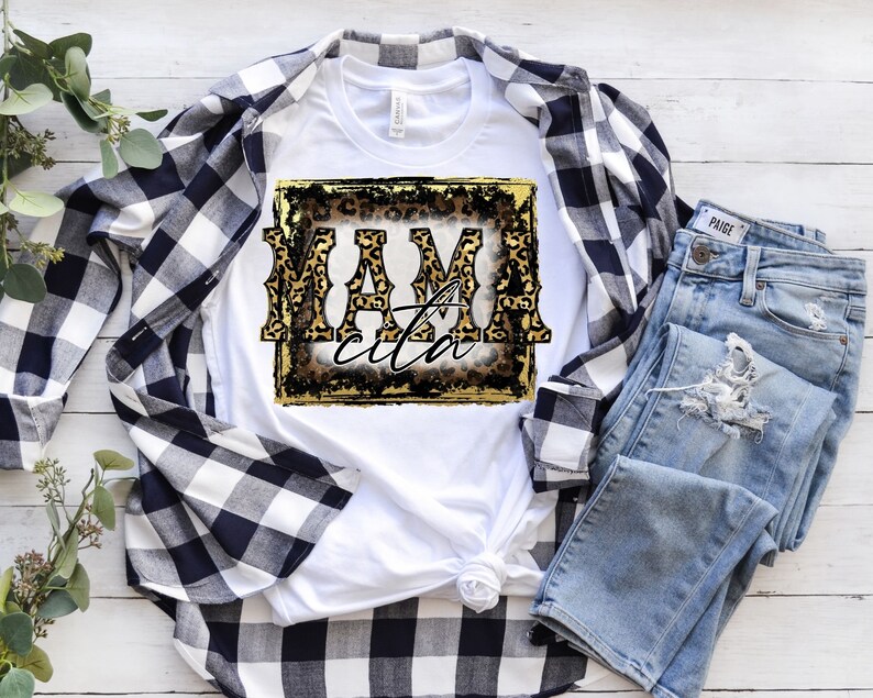 May include: White t-shirt with a gold and black graphic that says "Mamacita" in a leopard print font.
