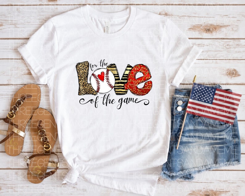 May include: White t-shirt with a graphic of the word "LOVE" with a baseball inside the "O". The letters are decorated with leopard print, stripes, and red glitter. The text "for the love of the game" is below the graphic.