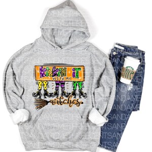 May include: A gray hooded sweatshirt with the text "Kickin' it with my witches" in orange, green, and purple. The text is surrounded by a cartoon image of witches with broomsticks.