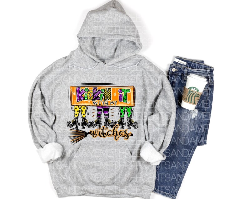 May include: A gray hooded sweatshirt with the text "Kickin' it with my witches" in orange, green, and purple. The text is surrounded by a cartoon image of witches with broomsticks.