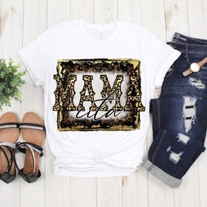 May include: White t-shirt with a gold and black graphic that says "Mamacita" in a leopard print font.