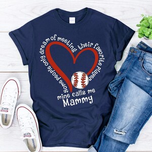 May include: Navy blue t-shirt with a red heart and a baseball graphic. The text on the shirt reads "Some people only dream of meeting their favorite player, mine calls me Mammy".