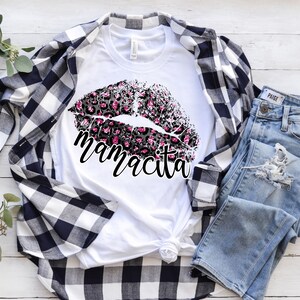 Pu&ograve; includere: Maglietta bianca con un design a labbra con stampa leopardata nera e rosa e il testo "mamacita" sotto.