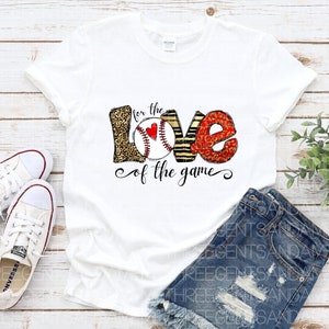 May include: White t-shirt with a graphic design of the word "love" with baseballs incorporated into the letters. The text "for the love of the game" is below the graphic.