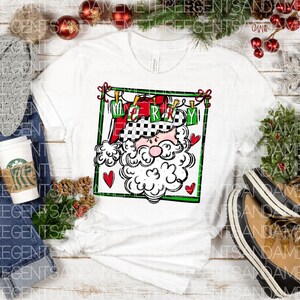 May include: White t-shirt with a black and white illustration of Santa Claus wearing a checkered hat and holding a sign that says "Merry". The illustration is surrounded by a red and green frame with hearts.