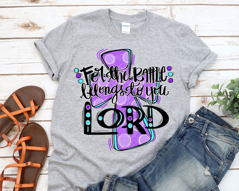 May include: A gray t-shirt with a purple cross and the text "For the battle belongs to you LORD" in black and blue lettering.