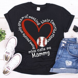 May include: Black t-shirt with a red heart and a baseball graphic. The text on the shirt reads "Some people only dream of meeting their favorite player, mine calls me Mammy."