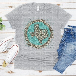 May include: A gray t-shirt with a turquoise and brown graphic of the state of Texas with a leopard print design. The graphic has a distressed look with white paint splatters.