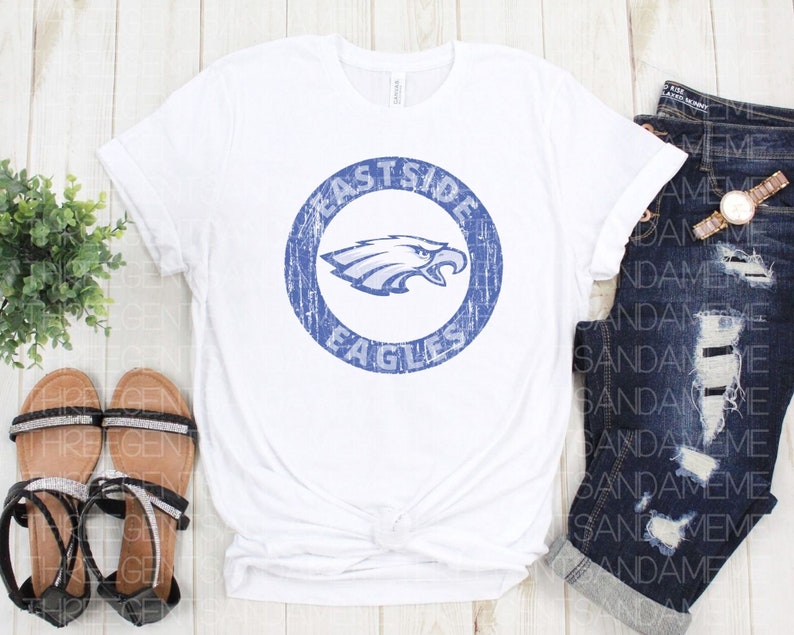 K&ouml;nnte beinhalten: Wei&szlig;es T-Shirt mit einem blauen, abgenutzten Kreis-Motiv, das einen Adler und den Text "Eastside Eagles" zeigt.