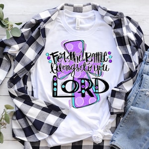 May include: White t-shirt with a purple cross design and the text "For the Battle belongs to you LORD!" in black lettering.