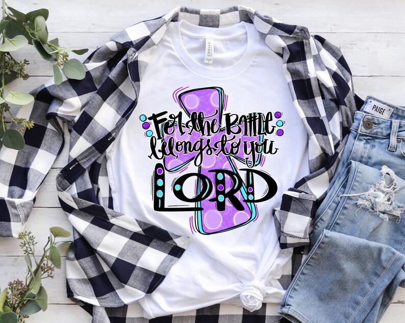 May include: White t-shirt with a purple cross design and the text "For the Battle belongs to you LORD!" in black lettering.