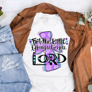 May include: White t-shirt with a purple and blue cross design. The text "For the battle belongs to you LORD" is written on the shirt.