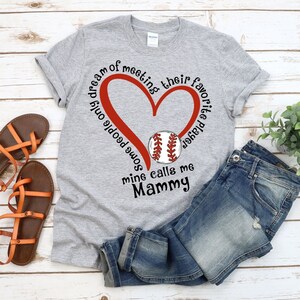 May include: Gray t-shirt with a red heart and a baseball graphic. The text on the shirt reads "Some people only dream of meeting their favorite player, mine calls me Mammy."