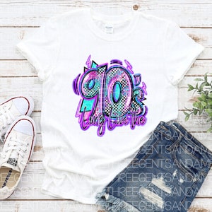 Pode incluir: Camiseta branca com um design gr&aacute;fico do n&uacute;mero 90's em uma fonte de estilo graffiti colorida com as palavras "Long Live the" abaixo.