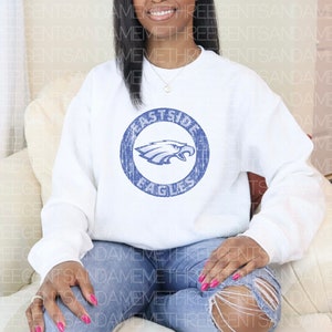 K&ouml;nnte beinhalten: Wei&szlig;er Pullover mit einem blauen, abgenutzten Kreis-Motiv, auf dem "Eastside Eagles" steht und ein blauer Adler im Kreis ist.