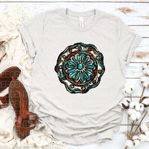 K&ouml;nnte beinhalten: Ein hellgraues T-Shirt mit einem t&uuml;rkisfarbenen und braunen Mandala-Design. Das Mandala hat ein blumenartiges Muster mit filigranen Details.