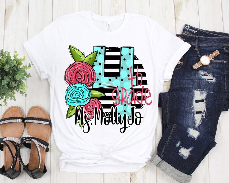May include: White t-shirt with a black and white striped design featuring a large number 4 with polka dots and the text "4th grade Ms. Molly Jo" in pink and blue lettering. The number 4 is decorated with pink and blue flowers.