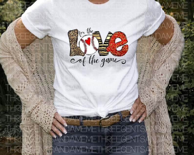 May include: White t-shirt with a graphic design of the word "love" with a baseball and the text "for the love of the game".