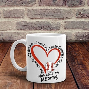 May include: White ceramic mug with a red heart and baseball graphic. The text reads "Some people only dream of meeting their favorite baseball player, mine calls me Mammy."