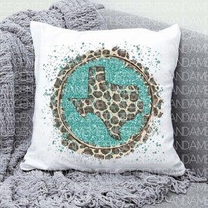 May include: A white pillow with a turquoise and brown glitter design of the state of Texas. The design is surrounded by a white splatter pattern.