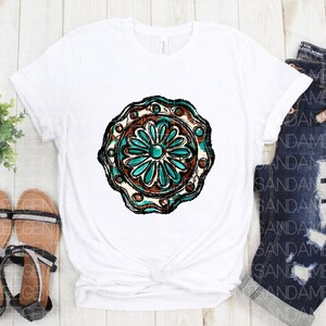 K&ouml;nnte beinhalten: Wei&szlig;es T-Shirt mit einem t&uuml;rkisfarbenen und braunen Mandala-Design. Das Mandala hat eine Blume in der Mitte mit einem t&uuml;rkisfarbenen Juwel.