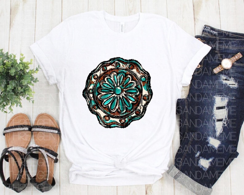 K&ouml;nnte beinhalten: Wei&szlig;es T-Shirt mit einem t&uuml;rkisfarbenen und braunen Mandala-Design. Das Mandala hat eine Blume in der Mitte mit einem t&uuml;rkisfarbenen Juwel.