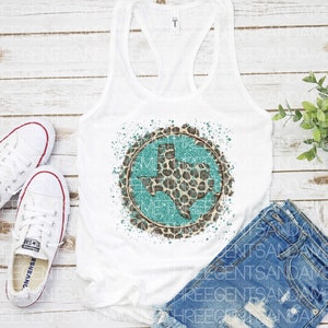 May include: White tank top with a turquoise and brown leopard print Texas state design. The design is in a circle with a white background and a turquoise outline. The tank top is laying on a white wooden surface.