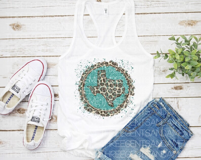 May include: White tank top with a turquoise and brown leopard print Texas state design. The design is in a circle with a white background and a turquoise outline. The tank top is laying on a white wooden surface.