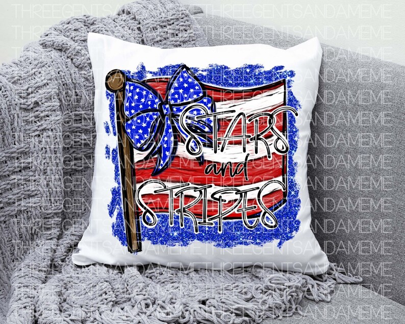 May include: A white pillow with a red, white, and blue American flag design. The flag has a blue bow with white stars on it. The text "Stars and Stripes" is written in black letters on the flag.