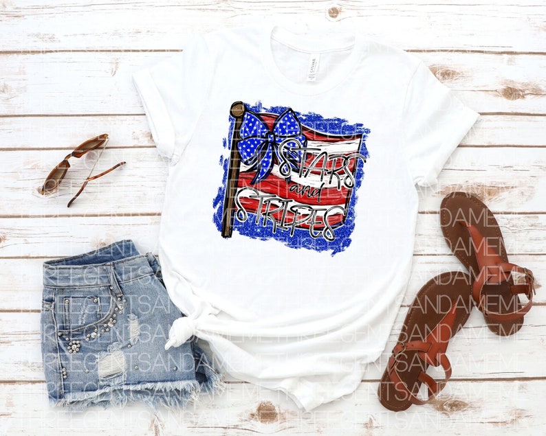 May include: White t-shirt with a distressed American flag design featuring a blue bow and the text "Stars and Stripes".
