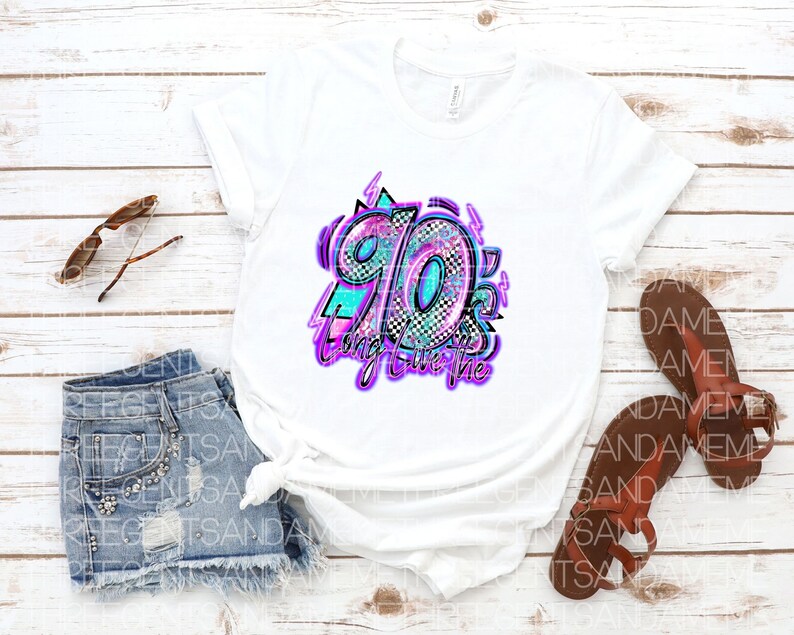 Pode incluir: Camiseta branca com um design gr&aacute;fico do n&uacute;mero 90 em um padr&atilde;o colorido, brilhante e xadrez. O texto "Bring it on the 90's" est&aacute; escrito em uma fonte roxa neon.