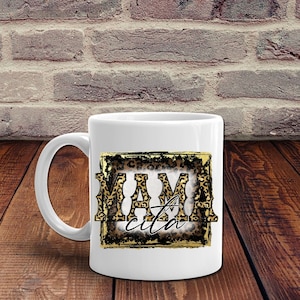 May include: White ceramic mug with a gold frame and leopard print design. The text "Mamacita" is inside the frame.