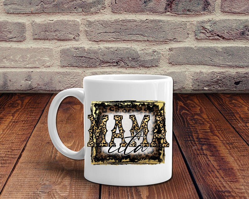 May include: White ceramic mug with a gold frame and leopard print design. The text "Mamacita" is inside the frame.