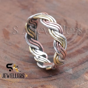 May include: A braided ring featuring interwoven strands of silver, gold, and rose gold. The ring's design showcases a textured, three-tone pattern. The ring is a piece of jewelry.