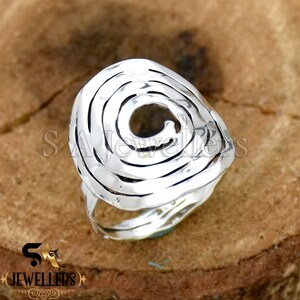 May include: A silver ring with a spiral design. The ring is made of hammered metal and has a textured finish.