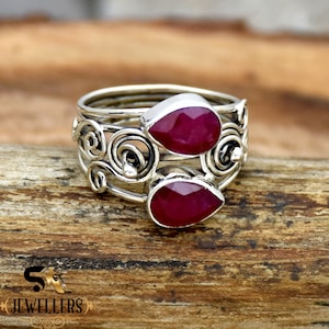 Puede incluir: Un anillo de plata con un diseño delicado y en espiral y dos piedras preciosas en forma de lágrima de rubí.