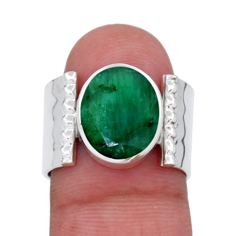 Puede incluir: Un anillo de plata con una gran esmeralda ovalada engastada en una banda texturizada.