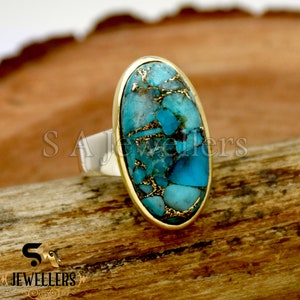 Könnte beinhalten: Ein ovaler Ring aus Türkis und Gold mit einem silbernen Band. Der Türkis-Stein ist eine Mischung aus Blau und Grün mit goldenen Flocken.