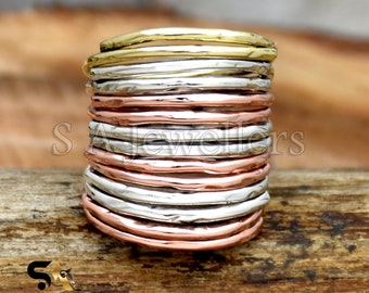 May include: A stack of 14 thin, hammered metal rings in silver, gold, and copper tones. The rings are stacked on top of each other to create a unique and stylish look.