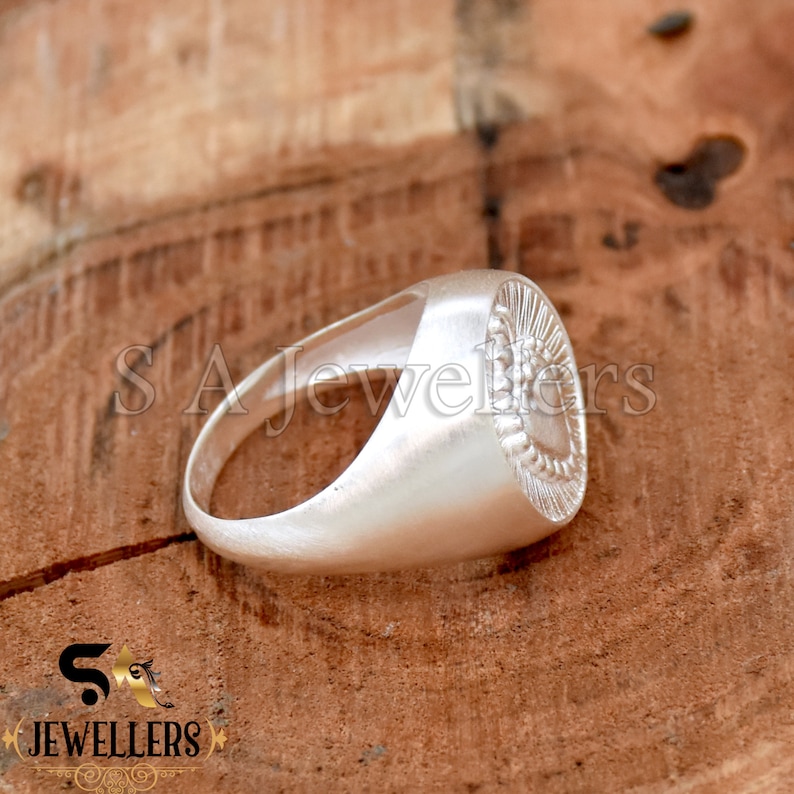 May include: A silver ring with a heart-shaped design on the top. The heart is surrounded by a circle of small dots.