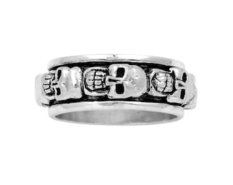 May include: Silver-toned ring featuring a repeating skull design around the band. The skulls are detailed with visible teeth and eye sockets. The ring has a polished finish and a classic, gothic aesthetic.