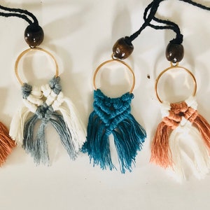 May include: Five macrame necklaces with gold rings and wooden beads. The macrame is in various colors, including peach, teal, gray, and white.