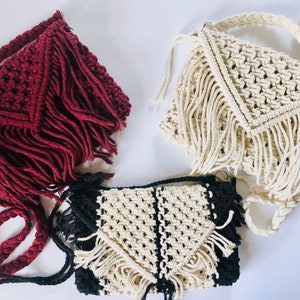 May include: Three crocheted bags with fringe. One bag is burgundy, one is white, and one is black and white.