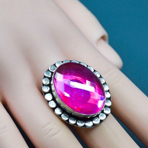 May include: A silver ring featuring a large, oval-shaped, iridescent pink gemstone set in a beaded bezel.