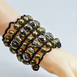 May include: A black elastic bracelet with gold and silver beads and faceted black stones.
